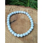 Bracelet en célestine 6 mm sur rondin de bois avec feuillage vert, perles bleu pastel, légèreté émotionnelle, clarté douce et bien-être serein