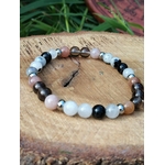 Bracelet Deuil 6 mm présenté sur plateau en bois avec feuillage vert, perles noires, blanches et rose pâle pour réconfort intérieur et stabilité émotionnelle