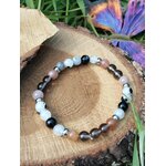 Bracelet Deuil sur rondin de bois avec feuillage et fleur en arrière-plan, ancrage doux, réconfort affectif et calme intérieur