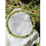 Bracelet jade du Canada 6 mm posé sur amas de quartz dans un décor nature, perles vert mousse, vert profond et nuances minérales, clarté douce, confiance et harmonie intérieure