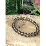 Bracelet obsidienne larme d’Apache 6 mm sur planche en bois clair avec feuillage vert, ancrage profond, réassurance émotionnelle et protection douce