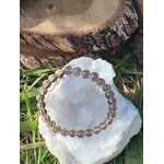 Bracelet obsidienne larme d’Apache 6 mm sur amas de quartz avec fond bois et feuillage, recul intérieur, stabilité nerveuse et énergie plus paisible