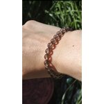Bracelet obsidienne larme d’Apache 6 mm porté au poignet sur fond feuillage vert, présence calme, protection symbolique et équilibre émotionnel