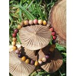 Bracelet mookaïte 6 mm aux tons terreux jaune ocre, crème, bordeaux et prune sur rondelles de bois parmi le feuillage vert, courage, stabilité et passage à l’action