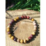 Bracelet mookaïte 6 mm aux tons terreux sur rondelles de bois parmi le feuillage vert, courage, passage à l’action et énergie d’enracinement