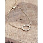 Bracelet doré acier inoxydable présenté à plat sur bois clair, chaîne fine et fermoir visibles, bijou élégant avec strass