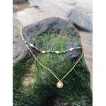Collier double chaîne dorée en acier inoxydable avec perles blanches, pierres vertes et médaillon nacré, posé sur une souche de bois recouverte de mousse verte, ambiance nature, lumière douce en Bretagne