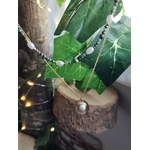 Collier double chaîne dorée acier inoxydable, perles blanches, pierres vertes, médaillon nacré, sur bois et feuilles vertes