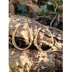 Boucles d’oreilles dorées 4 anneaux ovales reliés, détail étoile strassée, posées sur une écorce en décor nature avec feuilles et mousse en arrière-plan.