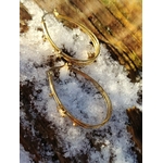 Boucles d’oreilles dorées à 4 anneaux ovales reliés, étoiles strassées, posées sur neige fondue avec décor bois en arrière-plan. en Bretagne