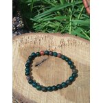 Bracelet jaspe héliotrope 6 mm sur rondin de bois, feuillage en fond ; ancrage, concentration, endurance.