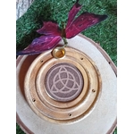 Porte-encens bois rond triquetra, posé sur mousse verte avec papillon rose en premier plan, fond clair, ambiance douce.