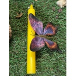 Bougie jaune plantée dans la mousse, papillon violet et orange, décor nature; clarté, joie, renouveau.