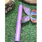 Bougie violette sur mousse, papillon violet-orange et pomme de pin floutée; intuition, calme, recentrage.