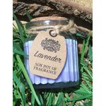 Bougie parfumée lavande en pot de verre strié violet avec couvercle en liège, ficelle et étiquette kraft, posée dans l’herbe en extérieur, lumière naturelle, ambiance fraîche, apaisante, détente, sérénité.
