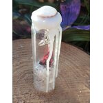 Spell jar en fiole de verre avec cristal de roche, fil rouge et cire blanche, posé sur bois avec décor sombre, ambiance protection et apaisement.