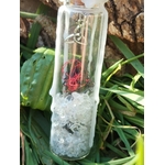 Spell jar en fiole de verre avec cristal de roche, fil rouge, cire blanche et breloque triquetra, photo en extérieur, énergie de protection et clarté.