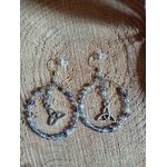 Boucles d’oreilles Hécate en fluorite facettée, création Magic Gaïa, anneaux perlés dégradés et breloques triquetra argentées, posées sur rondin de bois au soleil avec ombres rayées et verdure. Clarté, apaisement, concentration