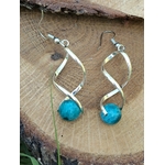 Boucles d’oreilles spirales argentées avec perles d’apatite bleue posées sur rondin de bois et décor végétal, clarté, motivation, confiance.
