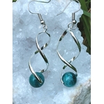 Boucles d’oreilles spirales argentées avec perles d’apatite bleue posées sur géode, clarté, motivation, communication.