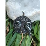 Pendentif viking verso argenté noirci avec gravure arbre sacré et spirales, posé devant mousse, feuillage vert et amas de quartz