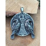 Gros plan sur pendentif viking argenté noirci avec arbre sacré, doubles corbeaux et spirales, posé sur  bois ton miel