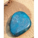 Galet d’apatite bleue poli posé sur support en bois clair, pierre naturelle reliée à la présence à soi, à la clarté d’esprit et au dynamisme doux.
