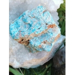 Apatite bleue brute sur fond blanc, éclats turquoise et veines ocre, pierre naturelle évoquant l’élan créatif, la présence à soi et la fluidité d’expression.