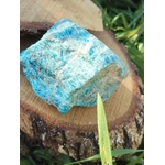 Apatite bleue brute bleu turquoise sur rondin de bois avec décor végétal naturel, pierre naturelle liée à la lucidité, à la créativité et à la communication sereine.