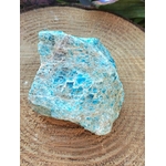 Apatite bleue brute sur rondin en bois aux éclats bleu lagon, pierre naturelle associée à la fraîcheur mentale, à l’inspiration et à la justesse intérieure.