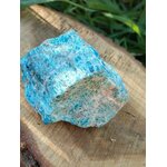 Apatite bleue brute sur rondin de bois avec décor végétal vert, pierre naturelle évoquant la motivation douce, le discernement et l’expression apaisée.