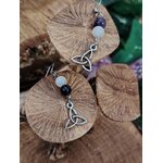 Boucles d’oreilles triquetra argenté avec perles d’améthyste et de sélénite, mises en scène sur champignon de bois en décor – Création Magic Gaïa – apporte apaisement, clarté, intuition.