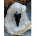 Pendule noir facetté sur chaîne argentée, posé sur un amas de quartz blanc scintillant, apporte protection, ancrage et clarté intérieure.