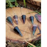 Ensemble de pendules en fluorite (violet/vert/bleu), décor nature sur tranche de bois, invite à calmer le mental et harmoniser l’énergie.