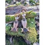 Duo de statuettes Gaïa en bois style wicca, spirale gravée et triquetra sur base triple lune, posées sur mousse et écorce en décor forêt; évoque ancrage, harmonie, protection douce, énergie féminine et connexion à la nature.