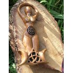 Statuette Gaïa (déesse) en bois style wicca avec spirale et triquetra, posée sur écorce dans un décor végétal; évoque ancrage, protection douce, harmonie, énergie féminine et intuition, idéale pour autel et déco ésotérique.