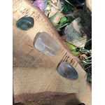 Lot de 3 pierres roulées Fluorite multicolore, nuances bleu-vert et violet, clarté mentale et apaisement, mise en scène sur tranche de bois en décor naturel.