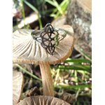 Bague ajustable motif nœud de sorcière, finition argentée, mise en scène sur champignon et herbes, ambiance nature; symbole d’union et d’équilibre.