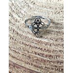 Bague réglable acier inoxydable argenté, nœud de sorcière ajouré, posée sur rondin de bois, ambiance naturelle; symbole de protection.