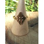 Bague réglable acier inoxydable doré, nœud de sorcière ajouré, sur cône beige, fond végétal flouté; symbole de protection.