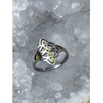 Bague réglable acier inoxydable argenté, nœud de sorcière ajouré, posée sur cristaux blancs (quartz), ambiance minérale; symbole de protection.