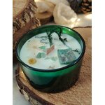 Bougie jade menthe-citron en cire de soja, pot en verre vert; cire blanche avec éclats de jade et fleurs séchées, posée sur rondin de bois, fond clair.
