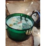 Gros plan bougie “jade” menthe-citron en cire de soja; verre vert, cire blanche ornée de pierres vertes, décor cocooning avec guirlande et pierre claire à côté.
