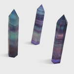 Lot de pointes de fluorite vert et violet à bandes sur fond blanc, pierres naturelles reliées à l’ordre des pensées, à la sérénité et à l’équilibre émotionnel.