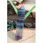 Pointe de fluorite à bandes bleu, vert et violet posée sur bois avec feuillage en décor, pierre naturelle évoquant la finesse d’esprit, la présence à soi et le calme du mental.