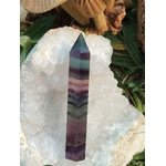 Pointe de fluorite à bandes vert, violet et bleu posée sur plaque de sélénite avec décor naturel, pierre naturelle associée à la fraîcheur intérieure, au relâchement et à la paix émotionnelle.
