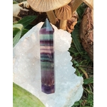 Pointe de fluorite à bandes bleues, violettes et vertes sur un amas de quartz avec décor végétal et bois, pierre naturelle liée à la concentration paisible, à l’ancrage mental et à l’harmonie.