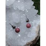 Boucles d’oreilles puces cornaline orange, tiges acier inoxydable, posées sur une géode de quartz; vitalité, motivation, confiance.
