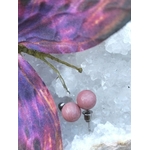 Boucles d’oreilles puces rhodonite rose, tiges acier inoxydable, posées sur une géode blanche avec papillon violet/rose en décor; ambiance douce, apaisement émotionnel et tendresse.