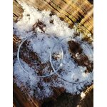 Boucles d’oreilles grandes créoles argentées en acier inoxydable, posées sur bois avec neige fondue; photo prise en Bretagne; évoquent fraîcheur, renouveau, clarté.